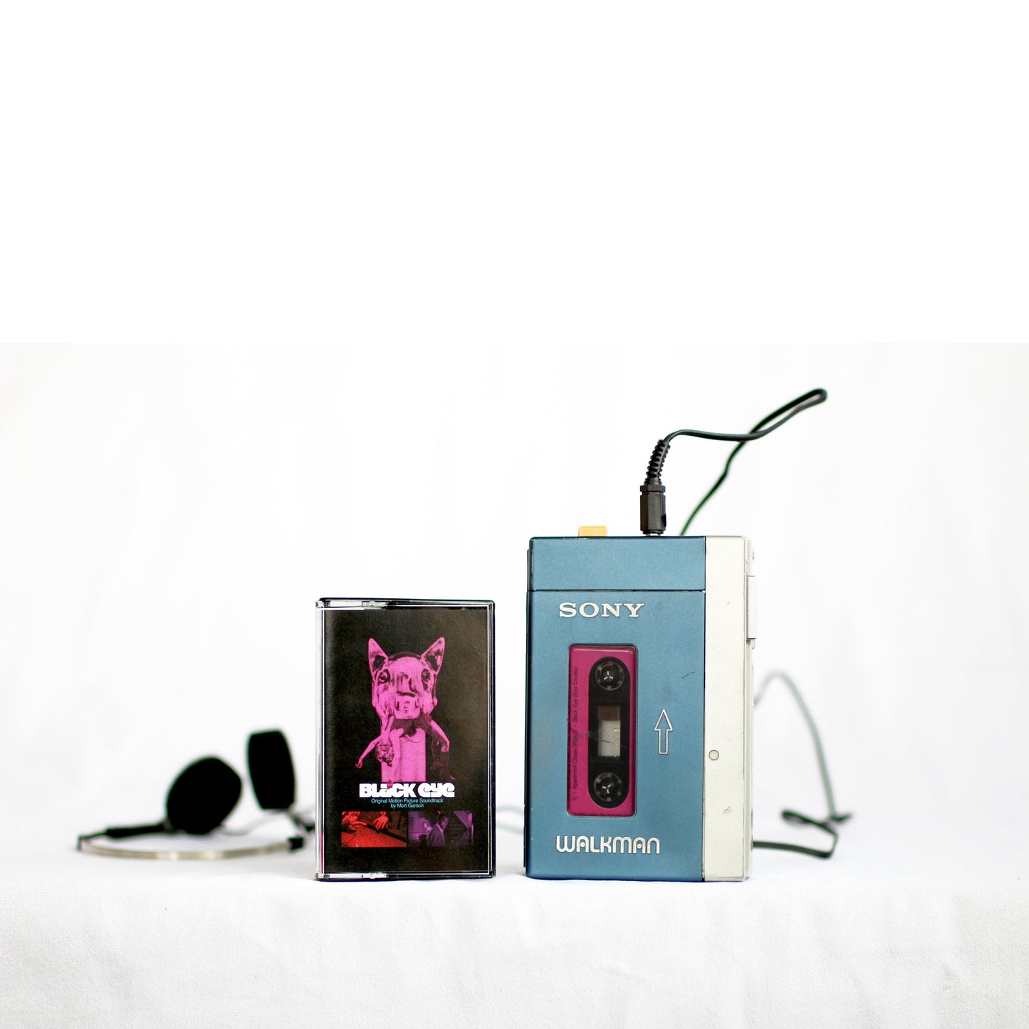 Black Eye cassette tape with vintage Sony Walkman and black headphones on white background
