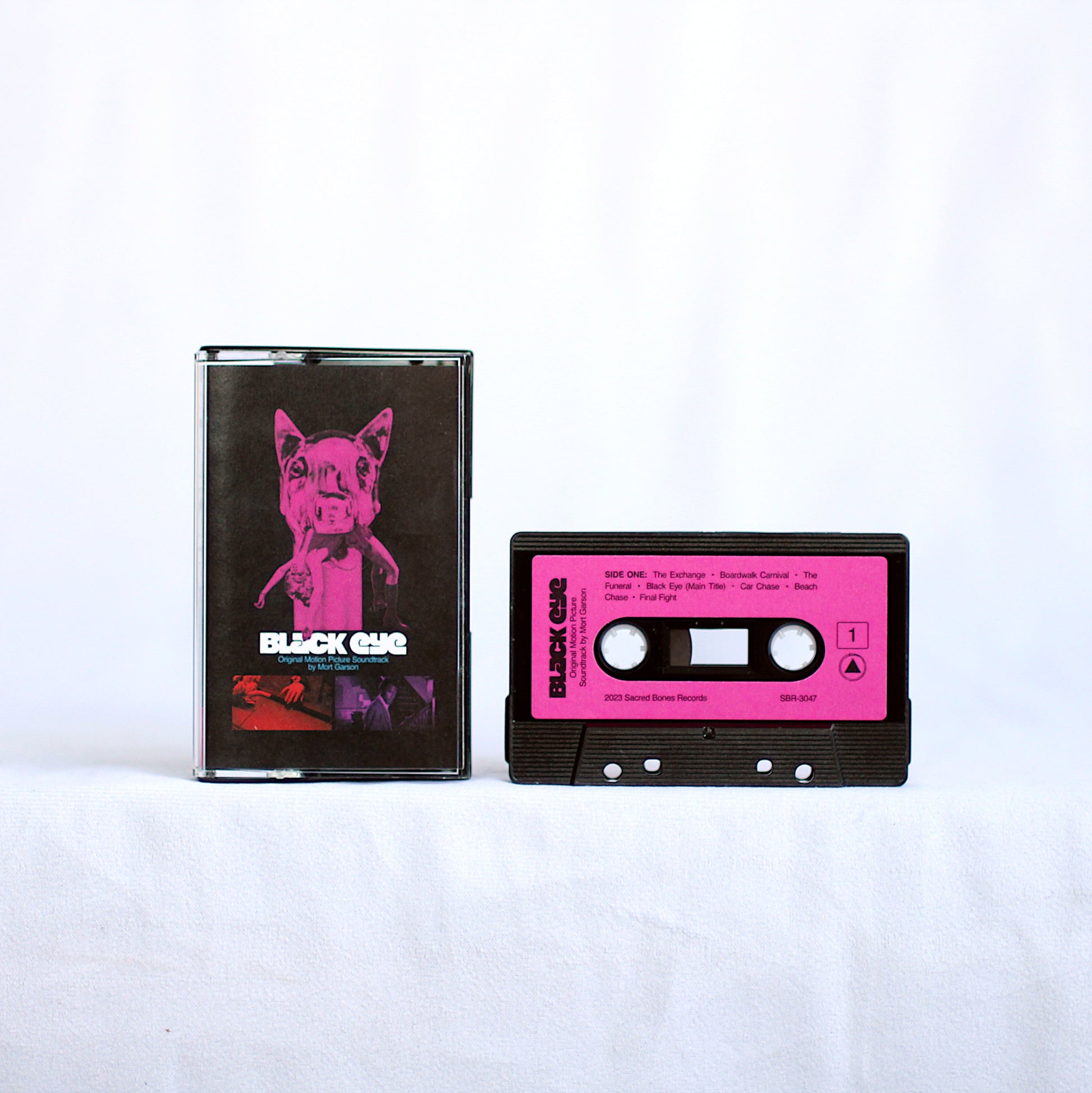 Black Eye cassette tape with bright pink label and black case featuring a pink dog illustration and white text
